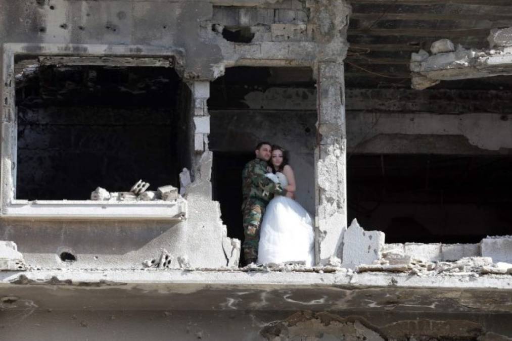 Nada Merhi, de 18 años, y Hassan Youssef, de 27, posan para el reportaje de fotos de su boda frente a los restos de un barrio bombardeado en la ciudad siria de Homs.