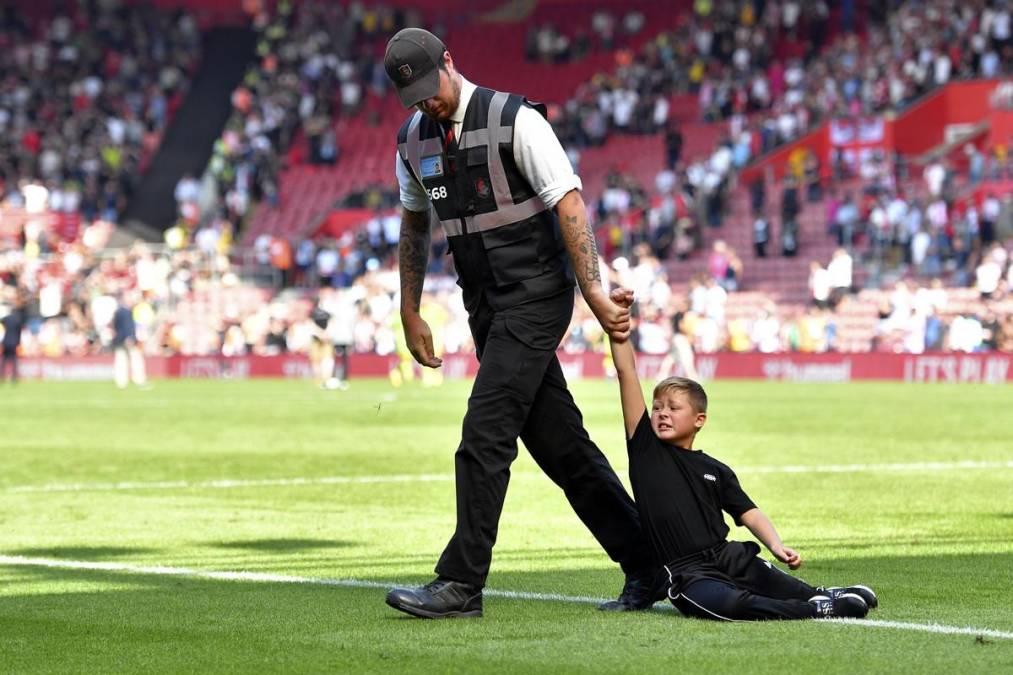 Un miembro de seguridad del St Mary’s Stadium sacando arrastrado a un pequeño intruso que se metió al terreno de juego.