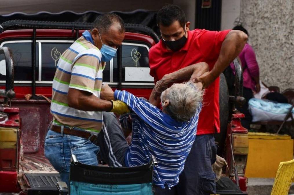 Un hombre con síntomas de COVID-19 es asistido por personas mientras espera atención médica en las carpas en el Hospital Escuela de Tegucigalpa. AFP