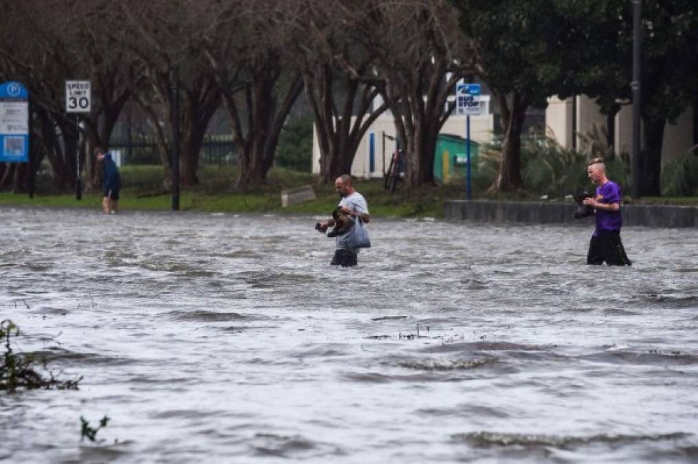 TOPSHOT - People cross a street flooded by Hurricane Sally in Pensacola, Florida, on September 16, 2020. - Hurricane Sally barrelled into the US Gulf Coast early Wednesday, with forecasts of drenching rains that could provoke 'historic' and potentially deadly flash floods. The National Hurricane Center (NHC) said the Category 2 storm hit Gulf Shores, Alabama at about 4:45 am (0945 GMT), bringing maximum sustained winds of about 105 miles (165 kilometers) per hour.'Historic life-threatening flooding likely along portions of the northern Gulf coast,' the Miami-based center had warned late Tuesday, adding the hurricane could dump up to 20 inches (50 centimeters) of rain in some areas. (Photo by CHANDAN KHANNA / AFP)