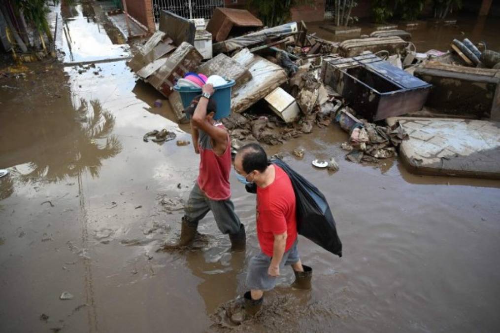 Men wade through the mud following the passage of Hurricane Eta in the municipality of Villanueva, department of Cortes, Honduras, on November 7, 2020. - Scores of people have died or remain unaccounted for as the remnants of Hurricane Eta unleashed floods and triggered landslides on its deadly march across Central America. (Photo by Orlando SIERRA / AFP)