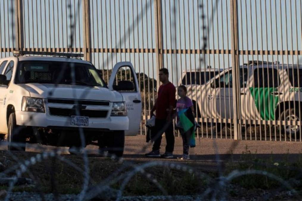 Honduran Andrea Nicolle, 10, and her father Tony, traveling in a caravan of Central American migrants hoping to get to the United States, walk to surrender to the Border Patrol after crossing through a hole on the ground under the metal barrier separating Mexico and the US to cross from Playas de Tijuana in Mexico into the US, on December 4, 2018. - Mexico's new Foreign Minister Marcelo Ebrard met with US Secretary of State Mike Pompeo for a 'friendly' meeting amid tensions over the migrant crisis at the border. Both countries are grappling with how to handle the thousands of Central American migrants who are camped at the common border -- in the short and long terms. (Photo by Guillermo Arias / AFP)