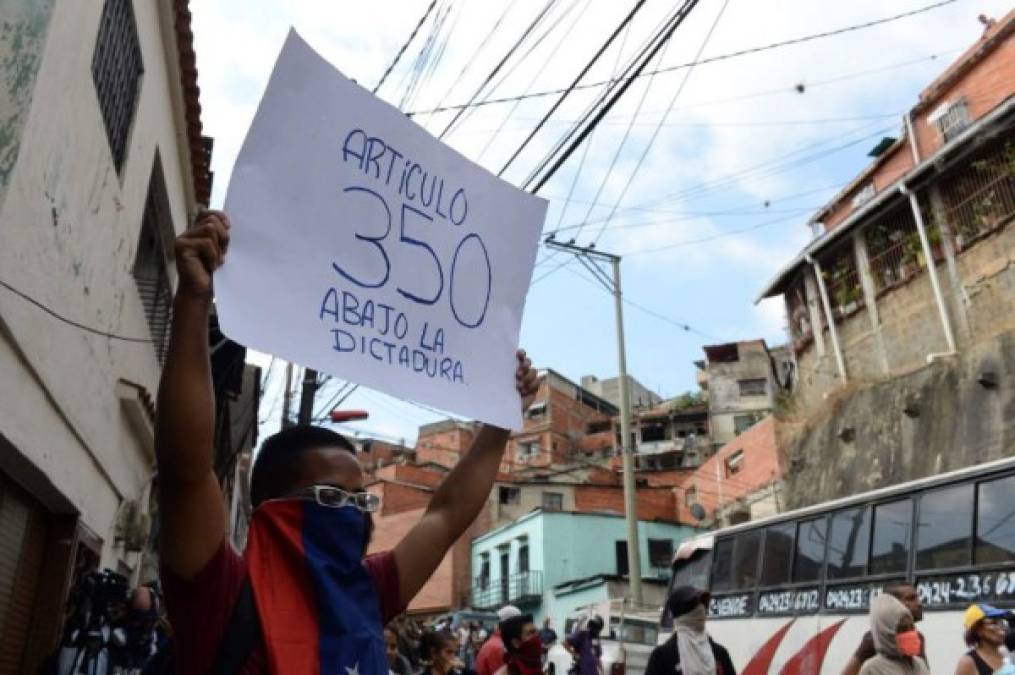 An anti-government demonstrator holds a placard reading 'Article 350. Down with the Dictatorship!' during clashes with police and troops in the surroundings of a National Guard command post in Cotiza, in northern Caracas, on January 21, 2019. - A group of soldiers rose up against Venezuela's President Nicolas Maduro at a command post in northern Caracas on Monday, but were quickly arrested after posting an appeal for public support in a video, the government said. (Photo by Federico PARRA / AFP)