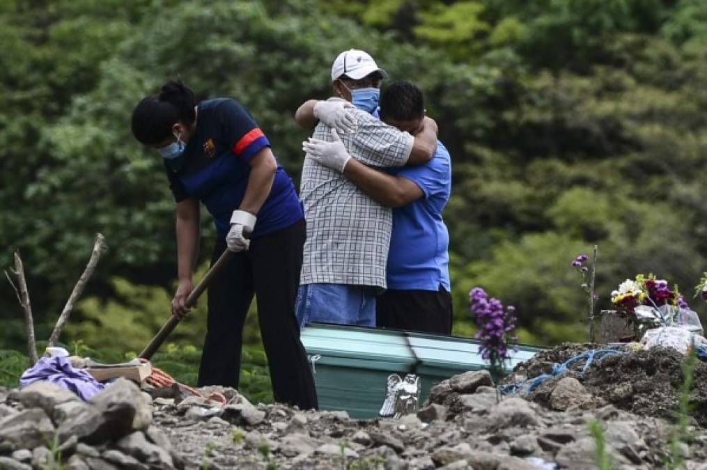 Men mourn during the burial of a COVID-19 victim at an annex of the Parque Memorial Jardin de Los Angeles cemetery, acquired by the municipality to bury people who died from the new coronavirus, 14 km north of Tegucigalpa on June 17, 2020. - Honduras has so far registered 9,658 contagions and 478 deaths from COVID-19. (Photo by ORLANDO SIERRA / AFP)