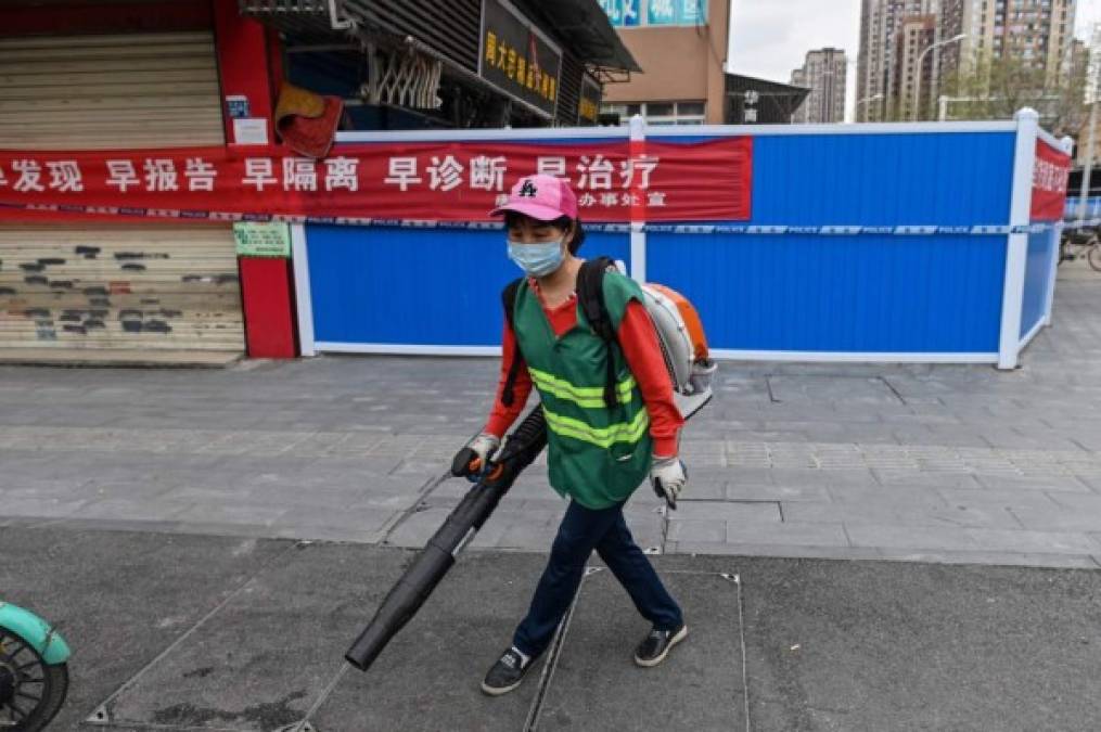 A delivery worker, wearing a face mask as a preventive measure against the spread of the COVID-19 novel coronavirus, waits to deliver items over a barrier in Wuhan, China's central Hubei province on April 20, 2020. - China's economy shrank for the first time in decades last quarter as the coronavirus paralysed the country, in a historic blow to the Communist Party's pledge of continued prosperity in return for unquestioned political power. The main access to the neighbourhood is on another street where workers take the temperatures of people and maintain the Wuhan health code. (Photo by Hector RETAMAL / AFP)