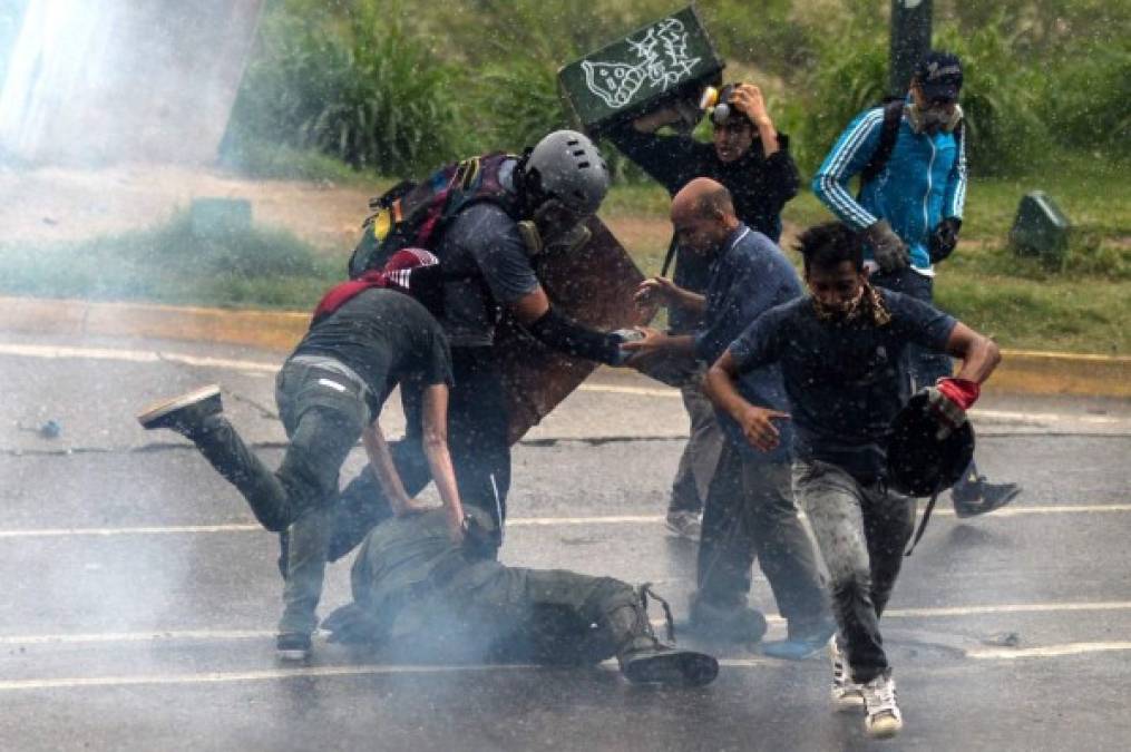 Manifestantes opositores patean a un miembro caído de las fuerzas de seguridad.