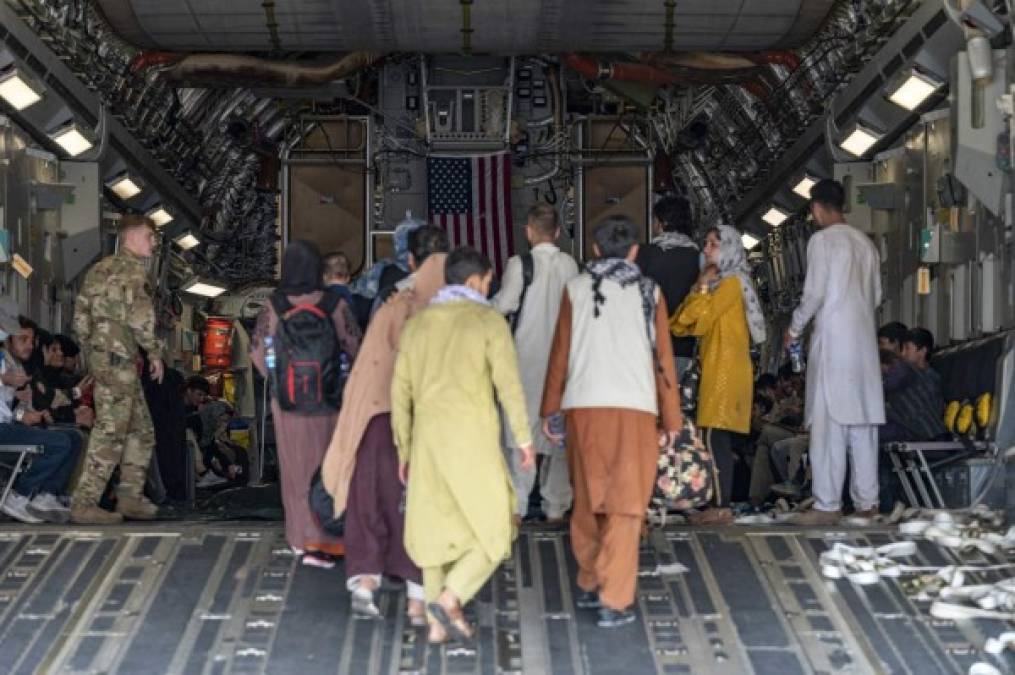 In this image courtesy of the US Air Force, a US Air Force loadmaster, assigned to the 816th Expeditionary Airlift Squadron, assists evacuees aboard a C-17 Globemaster III aircraft in support of Operation Allies Refuge at Hamid Karzai International Airport (HKIA), Kabul, Afghanistan, on August 20, 2021. (Photo by Taylor Crul / US AIR FORCE / AFP) / RESTRICTED TO EDITORIAL USE - MANDATORY CREDIT 'AFP PHOTO / Taylor Crul / US AIR FORCE' - NO MARKETING - NO ADVERTISING CAMPAIGNS - DISTRIBUTED AS A SERVICE TO CLIENTS