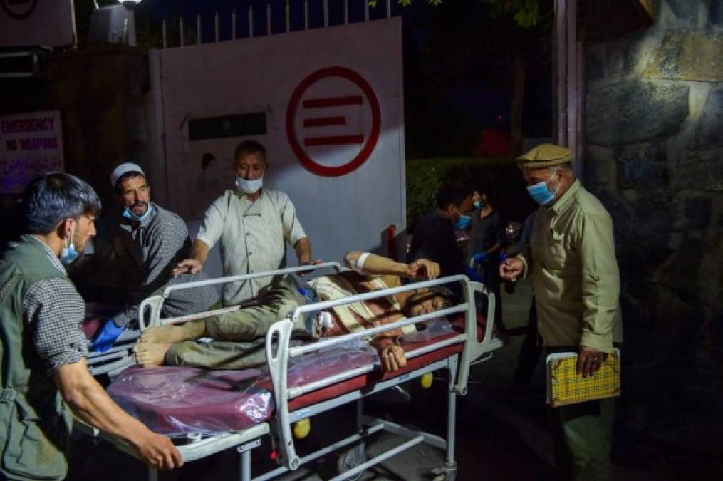 EDITORS NOTE: Graphic content / Medical and hospital staff bring an injured man on a stretcher for treatment after two powerful explosions, which killed at least six people, outside the airport in Kabul on August 26, 2021. (Photo by Wakil KOHSAR / AFP)
