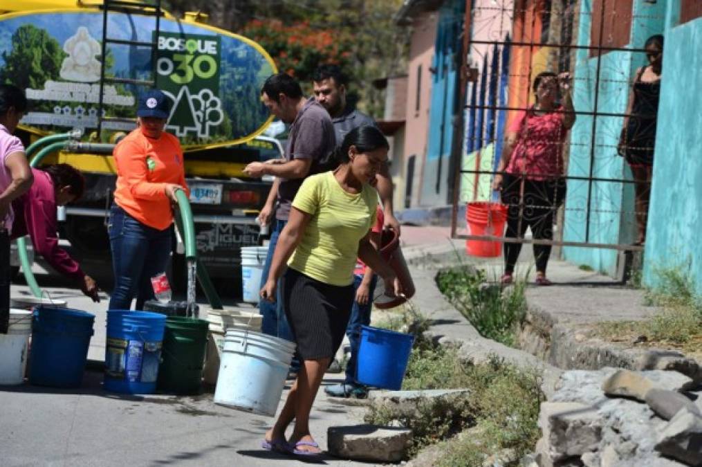 Los residentes del barrio de San Francisco de Tegucigalpa llevan agua potable de un camión cisterna el 12 de febrero de 2020. Al menos medio millón de personas, que viven en 139 vecindarios y asentamientos en la capital hondureña, comenzaron a recibir agua bajo el 'Plan Agua para Tu Barrio', que el gobierno implementó debido a los bajos niveles de los embalses de La Concepción y Los Laureles, que abastecen a más de un millón de habitantes de la capital hondureña. Fotos: AFP