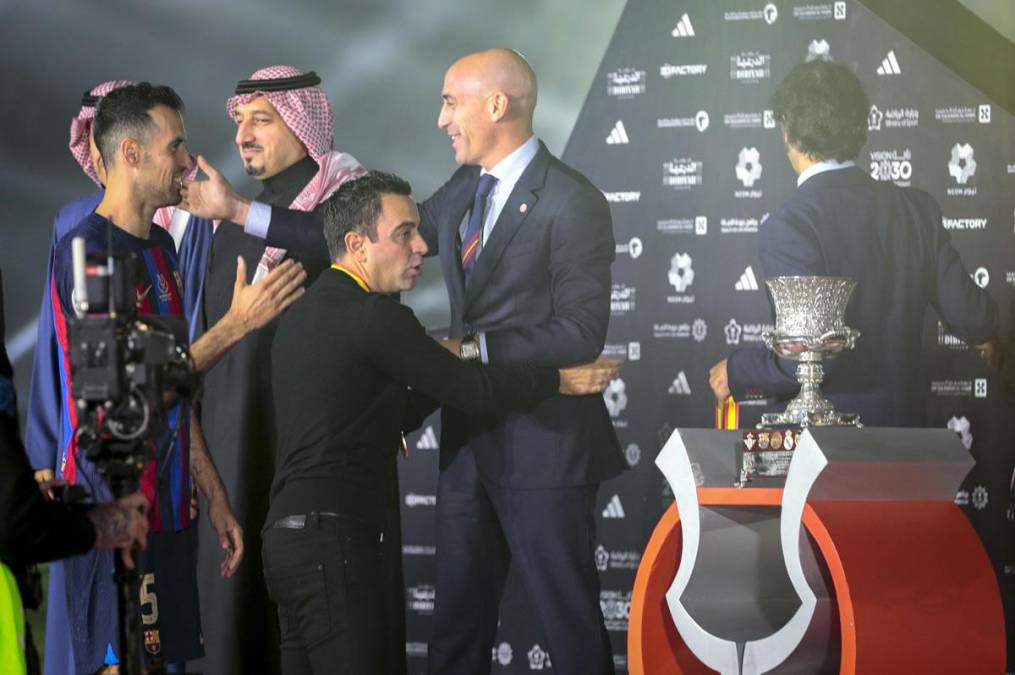 Xavi Hernández y Sergio Busquets pasando a recoger las medallas de campeones de la Supercopa de España.