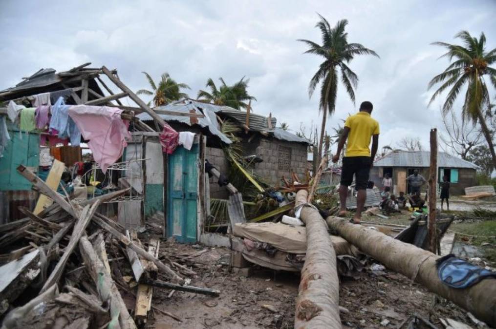 Un hombre camina sobre una palmera en el frente de una casa destruida después del huracán Matthew.