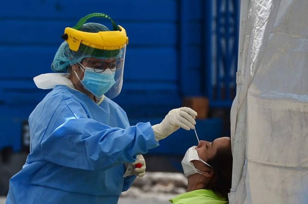 Toman muestra para una prueba de COVID-19 en una de las cuatro carpas instaladas para tratar casos del nuevo coronavirus en el estacionamiento del Hospital Escuela de Tegucigalpa. AFP