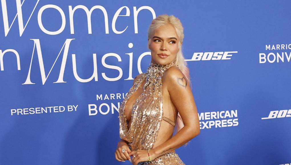 El resto del vestido también estaba adornado con cristales blancos dispersos y pequeñas cuentas, pero Karol G no se limitó al brillo; Agregó un par de zapatos plateados brillantes y un anillo de diamantes. La cantante lució un llamativo maquillaje brillante, uñas mate y una sencilla coleta. Sobresalió un brillante en unos de sus dientes, una tendencia en auge actualmente entre las celebridades.