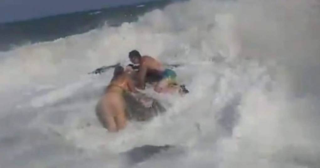 Ambos logran sujetarse a la roca mientras son golpeados por las fuertes olas.