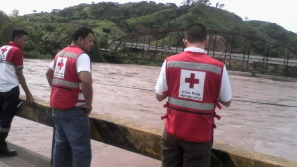 Tres elementos de la Cruz Roja Hondureña contemplan el nivel del río Ulúa en Pimienta, Cortés.