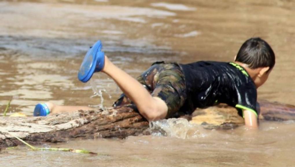 Niños hondureños se bañan en aguas estancadas por Iota