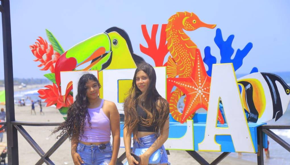 Dos bellas jóvenes posan en el letrero de Tela.