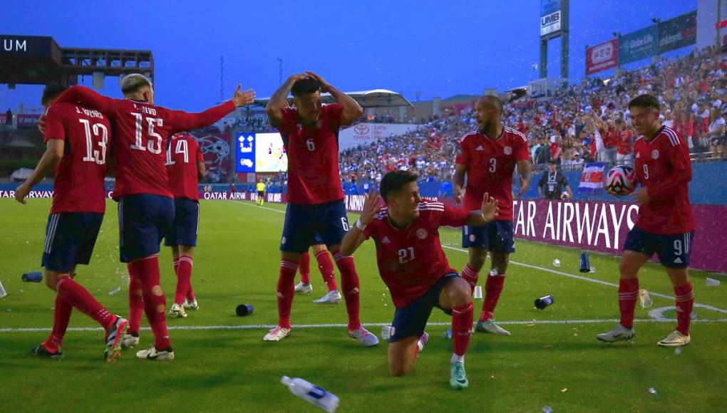 Jugadores de Costa Rica celebran un gol ante Honduras mientras son golpeados con botellas plásticas que lanzaron los aficionados hondureños.