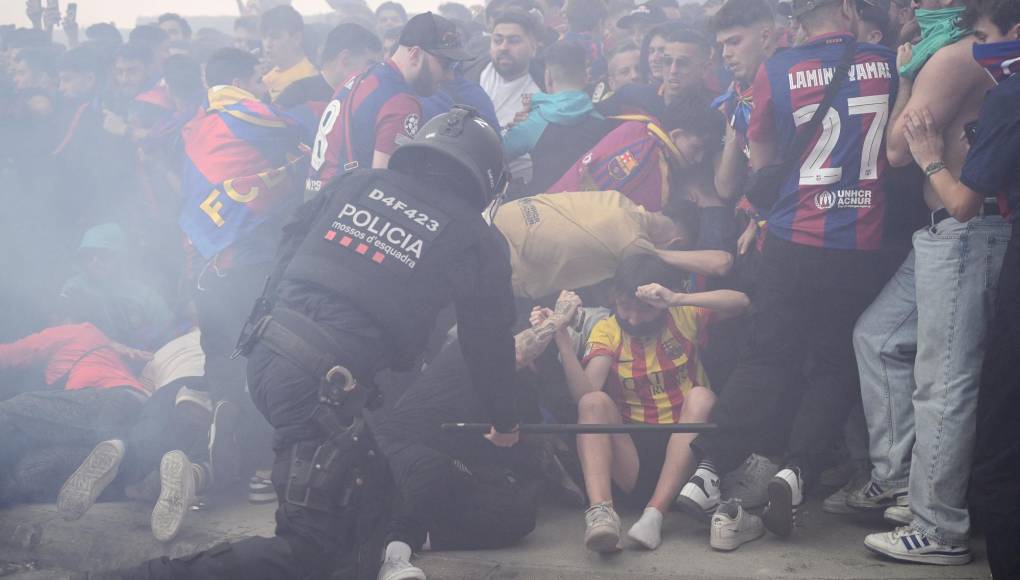Un policía golpea a los aficionados en los disturbios que se dieron previo al inicio del Barcelona y PSG.