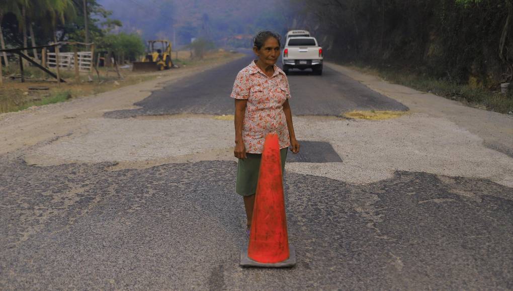 <b>La señora María Amaya tapa un bache que recién “nació” a la par de uno que fue tapado con cemento. En los municipios de El Negrito y Morazán también han replicado en trabajo de la juventud de Yoro y han tapado muchos agujeros con mezcla de cemento y arena.</b>