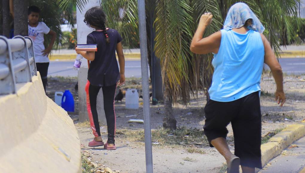 Esta señora pide dinero junto a estos dos menores que limpian vidrios.