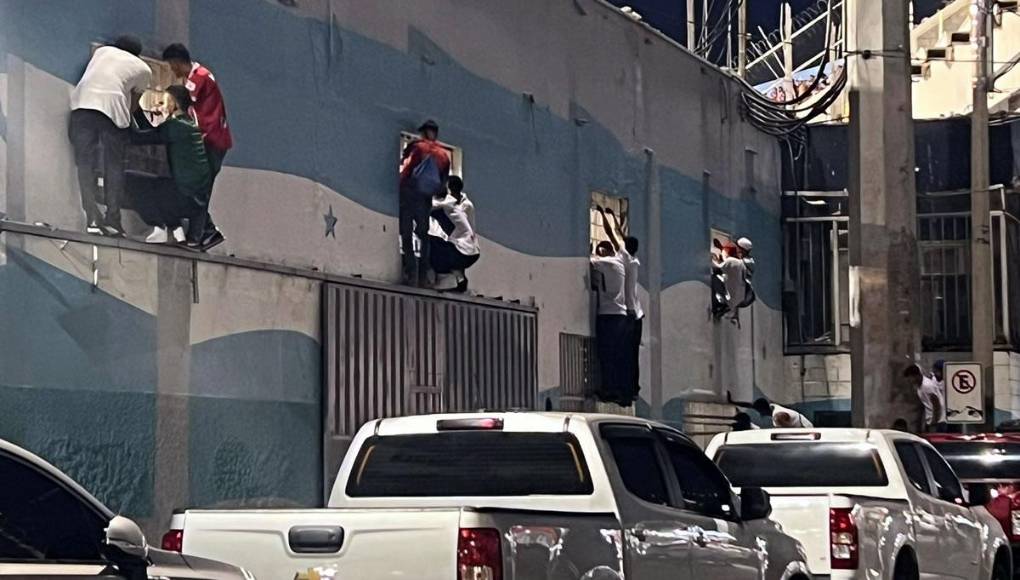 Aficionados que no pudieron ingresar al estadio estadio Nacional Chelato Uclés observan el partido entre Olimpia y Marathón desde las ventanas enrejadas del área en construcción del coloso capitalino.