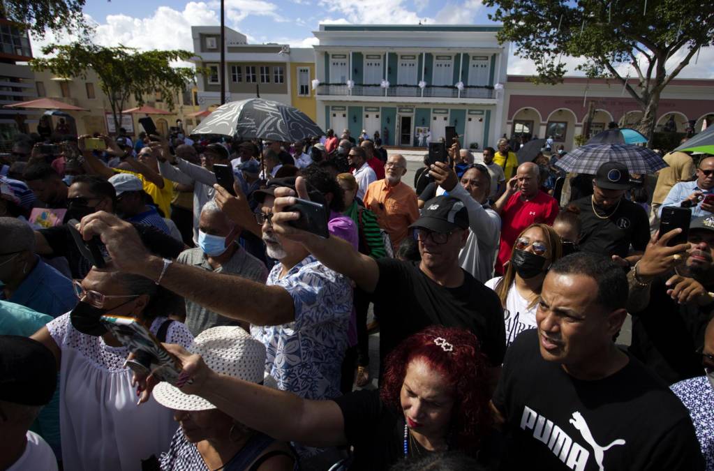 Varias personas observan el paso de la carroza fúnebre que carga el ataúd del salsero puertorriqueño Lalo Rodríguez, hoy, en Carolina (Puerto Rico). 