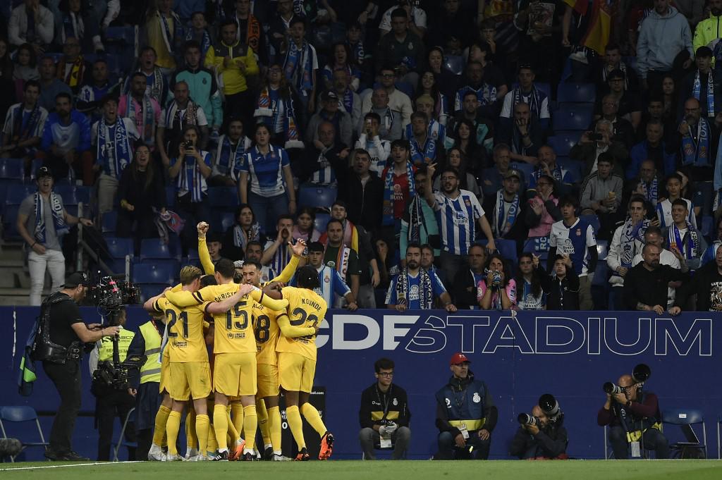 Jugadores del FC Barcelona celebrando mientras en el fondo se lamentan los aficionados del Espanyol.