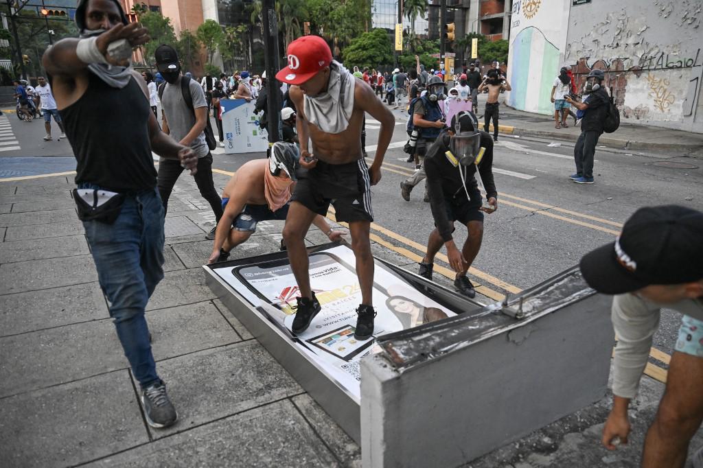 Los manifestantes desmontan una pancarta callejera con publicidad durante una protesta contra el gobierno del presidente venezolano Nicolás Maduro en Caracas el 29 de julio de 2024.