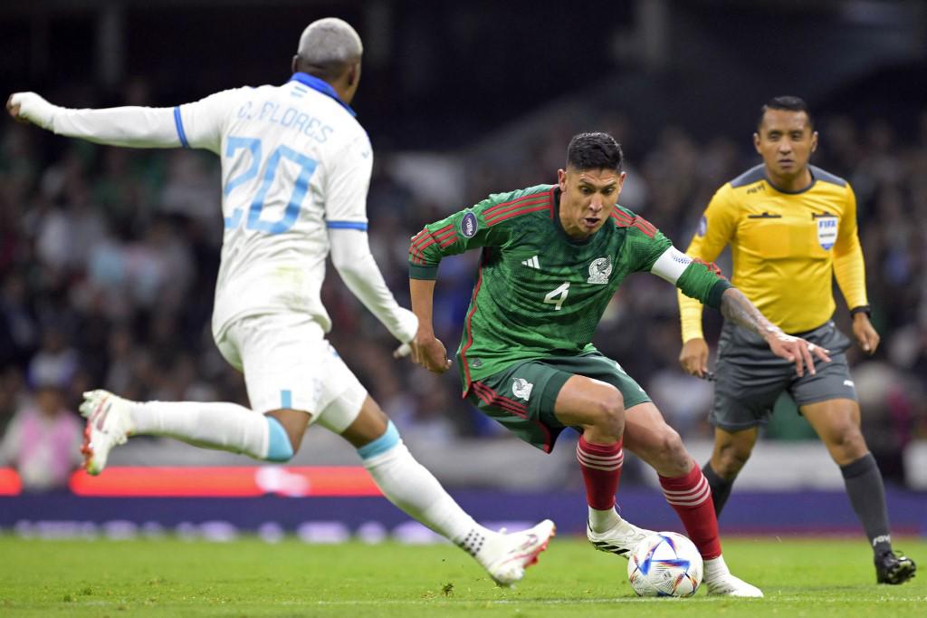 Edson Álvarez de México disputa el balón con Deybi Flores. En el fondo aparece el árbitro salvadoreño Iván Bartón.