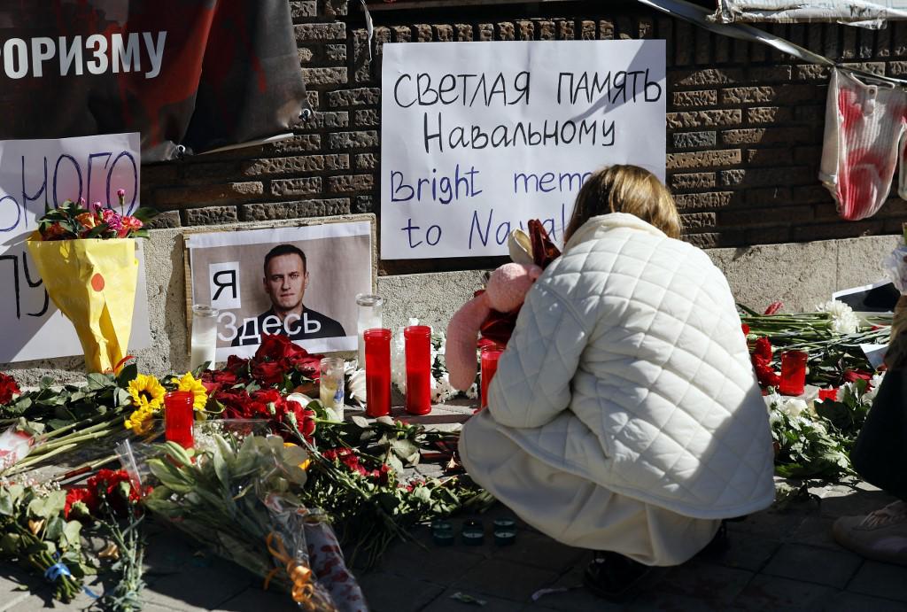 Una niña mira las flores y velas colocadas frente a la embajada rusa en Madrid el 17 de febrero de 2024, un día después de que funcionarios rusos anunciaran la muerte del crítico más destacado del Kremlin, Alexei Navalny.
