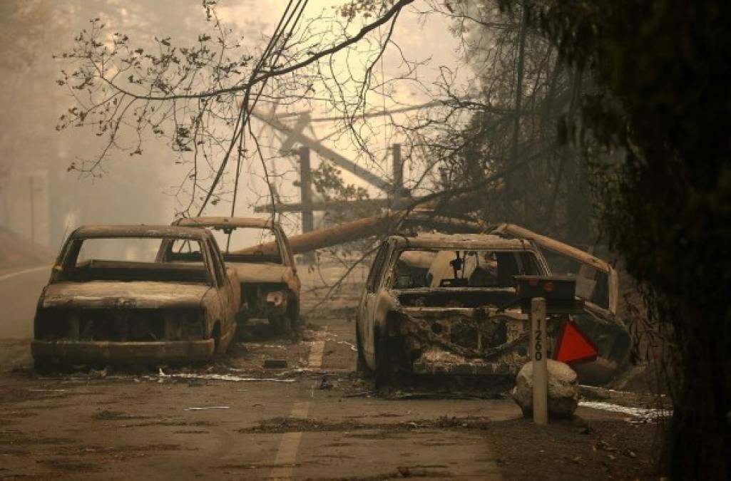 PARADISE, CA - NOVEMBER 10: Power lines rest on cars that were burned by the Camp Fire on November 10, 2018 in Paradise, California. Fueled by high winds and low humidity, the rapidly spreading Camp Fire ripped through the town of Paradise and has quickly charred 100,000 acres and has destroyed over 6,700 homes and businesses in a matter of hours. The fire is currently at 20 percent containment. Justin Sullivan/Getty Images/AFP