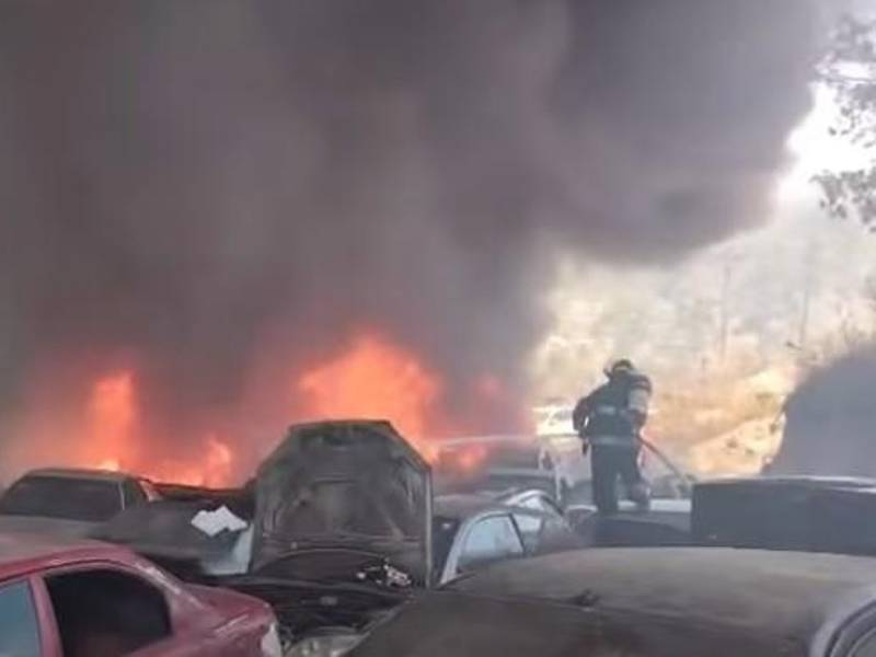Un bombero lanza agua con una manguera para sofocar uno de los vehículos en llamas durante el incendio registrado en un yonker de Cerro Grande.