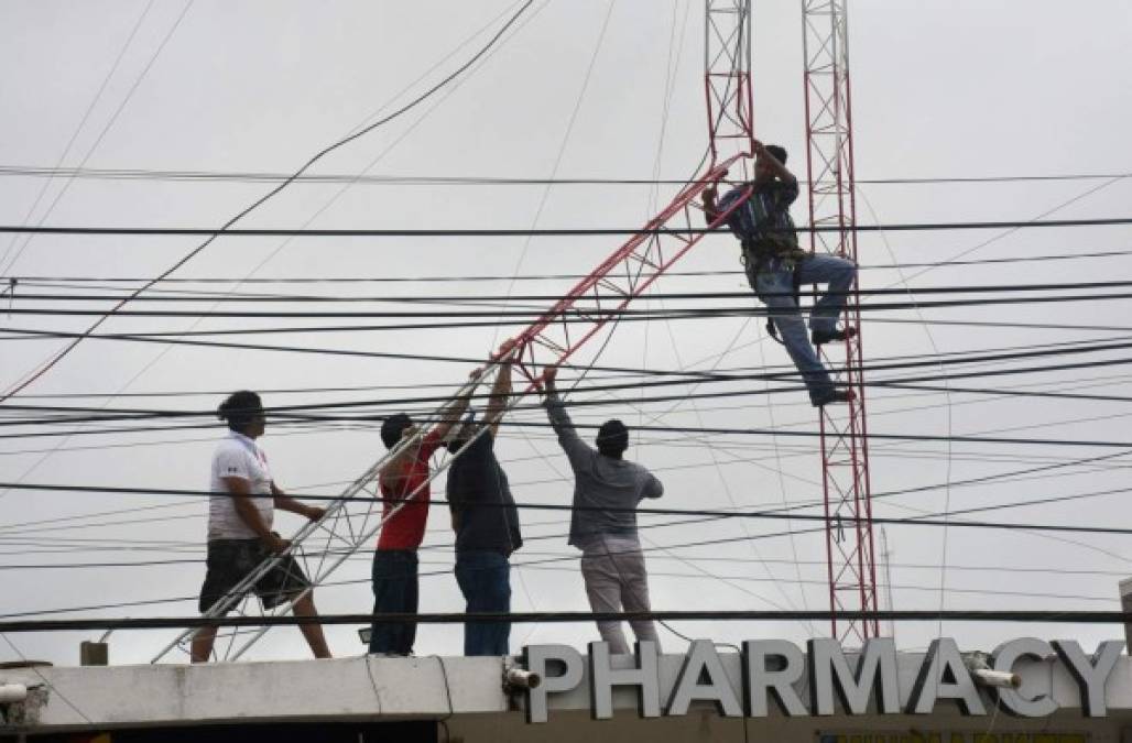 Local workers repair a building's communications antenna after the passage of Hurricane Grace through the coast of Tulum, state of Quintana Roo, Mexico, on August 19, 2021. - Hurricane Grace made landfall along Mexico's eastern Yucatan peninsula on Thursday, clocking winds of 80 miles (130 kilometers) per hour as the National Hurricane Center warned of a 'dangerous storm surge' in the area. (Photo by ELIZABETH RUIZ / AFP)