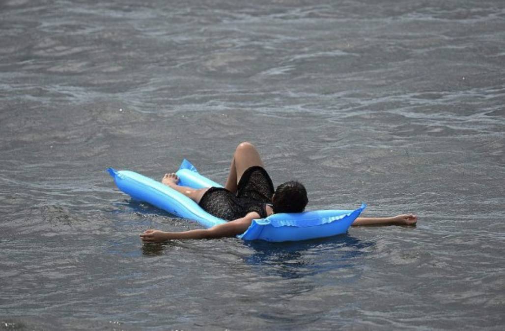 Una mujer disfruta flotando en una cama inflable durante Semana Santa. (AFP)