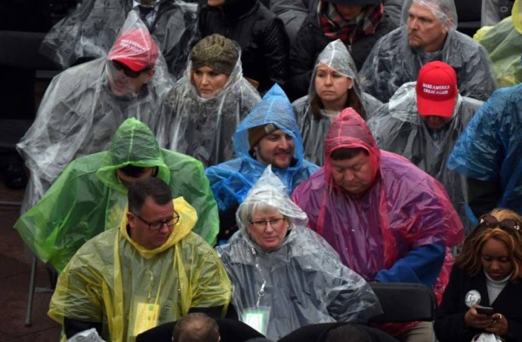 Los asistentes a la toma de posesión se resguardan con ponchos de la lluvia que cae en Washington DC esta mañana.