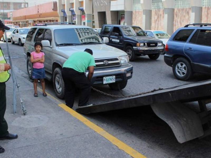 Policías municipales levantan carros con grúas cuando son estacionados en espacios prohibidos.