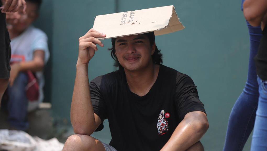 Con banderas de gorros, cartones como sombreros y agua para hidratarse, esperan pacientemente bajo el infernal sol que baña a San Pedro Sula con sus inclemente fuerza.