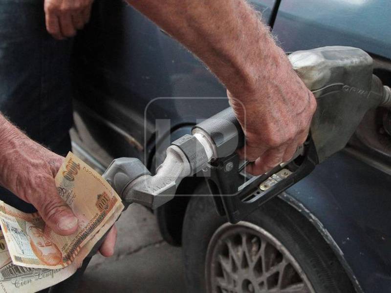 Un empleado sirve combustible en una estación.