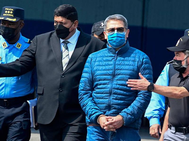 El expresidente de Honduras, Juan Orlando Hernández (2-D), es escoltado por el ministro de Seguridad, Ramón Sabillon (D), hacia un avión de la Agencia Antidrogas de EE. UU. (DEA)