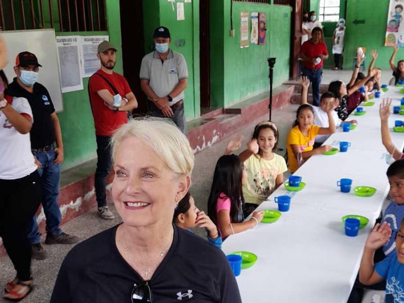 La embajadora de Estados Unidos ante las agencias de la Organización de las Naciones Unidas (ONU) en Roma, Cindy H. McCain, sonríe junto a los niños que comen su merienda.