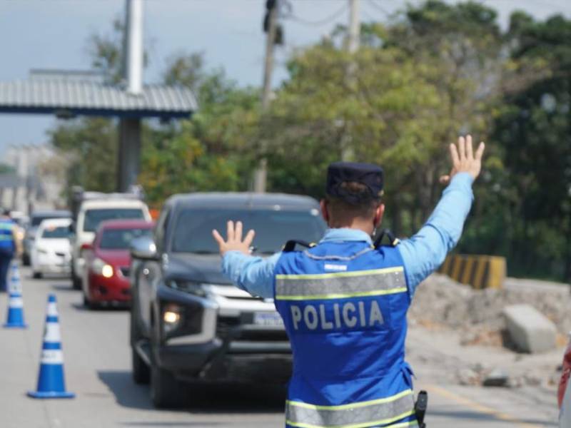 Un agente de la Policía realiza la señal de detenerse a un conductor de una camioneta en el bulevar del este de San Pedro Sula.