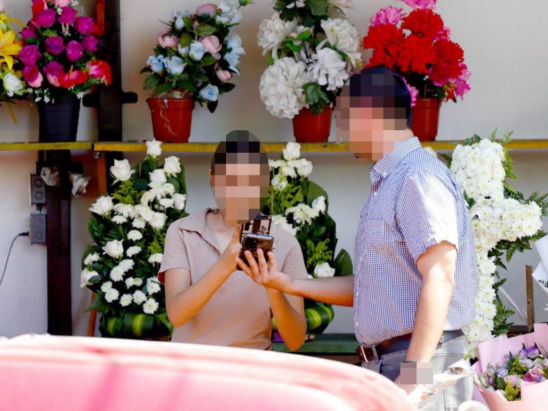Una joven vendedora de flores en el barrio Guamilito toma fotografía al comprobante de transferencia bancaria realizado: La joven no corroboró que el dinero fue depositado en su cuenta.