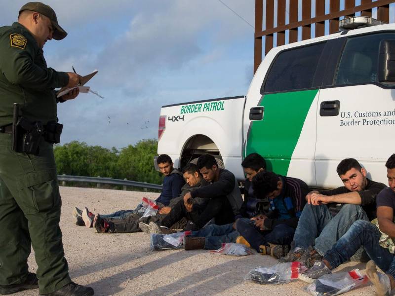 Un agente de la Patrulla Fronteriza detienen a un grupo de inmigrantes indocumentados en la frontera.