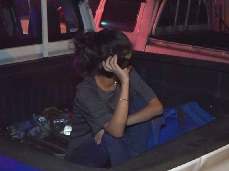 Joven detenida en la paila de una patrulla.