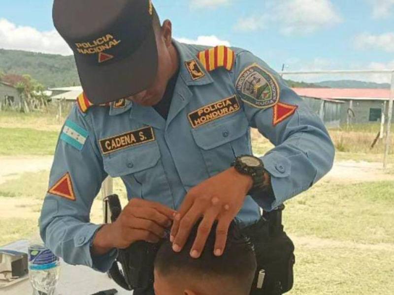 Miembro de la Policía Nacional corta el cabello de un niño en Intibucá.
