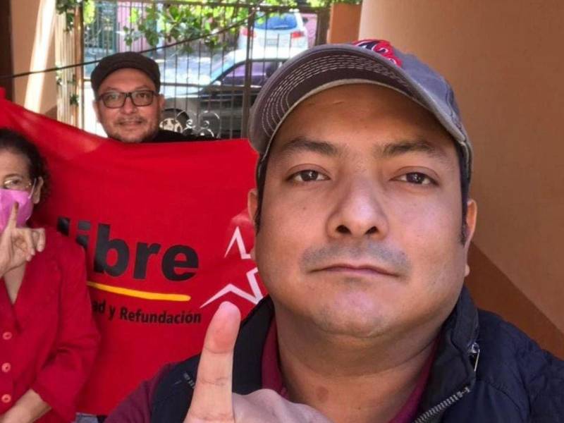 La doctora Nerza Paz muestra su dedo entintado tras ejercer el sufragio, acompañada de sus hijos Vladimir y Néstor Rodríguez Paz, con una bandera del Partido Libertad y Refundación (Libre).