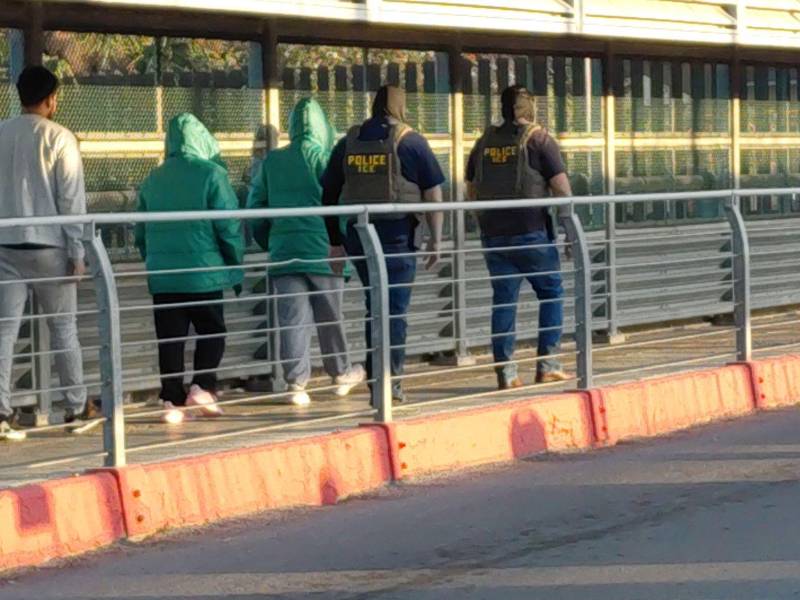 Un grupo de migrantes es llevado por el puente internacional McAllen-Hidalgo por un grupo de agentes del Servicio de Inmigración y Control de Aduanas de Estados Unidos (ICE, por sus siglas en inglés).