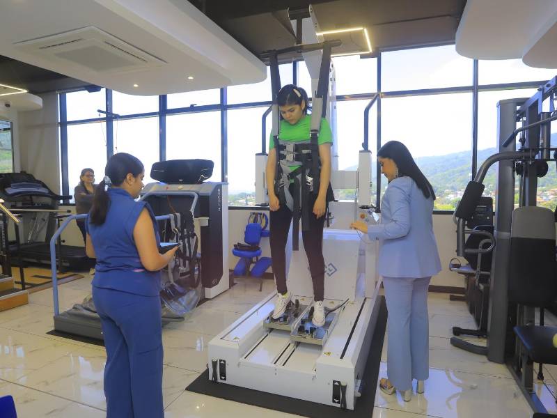 En esta imagen bservamos a una joven haciendo uso del R-Gait, una máquina de rehabilitación diseñada para reeducar la marcha humana.