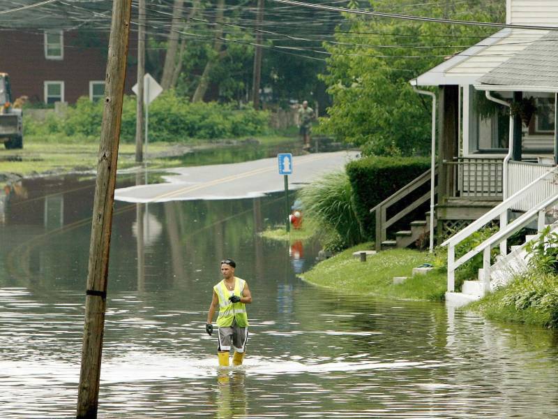 Un trabajador municipal camina por la zona inundada del río Delaware en una calle de Morrisville, en Pensilvania.